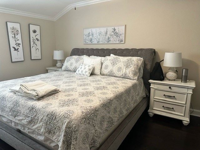 bedroom featuring ornamental molding, vaulted ceiling, and dark hardwood / wood-style floors