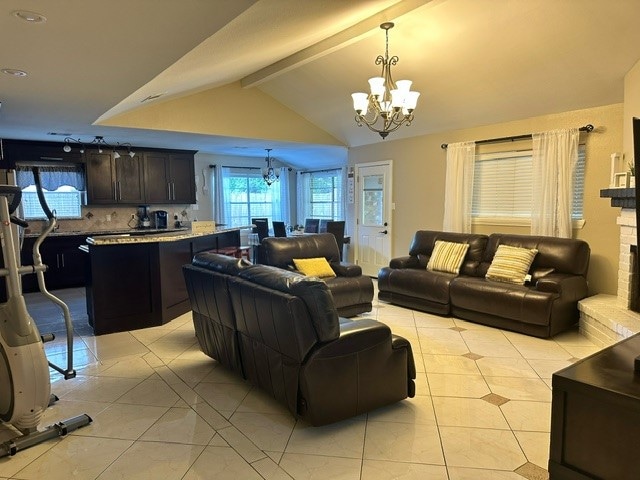 living room with an inviting chandelier, light tile patterned floors, a brick fireplace, and vaulted ceiling with beams