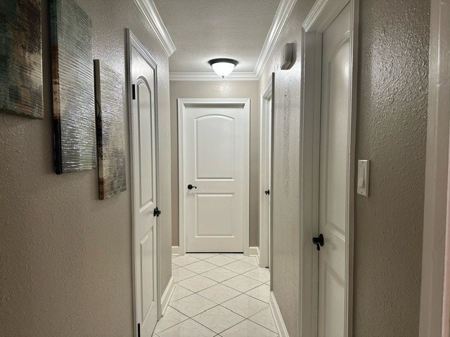 hallway with a textured ceiling, crown molding, and light tile patterned floors