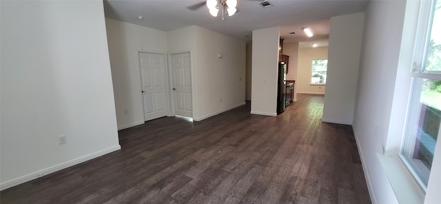 empty room with dark wood finished floors, visible vents, baseboards, and ceiling fan