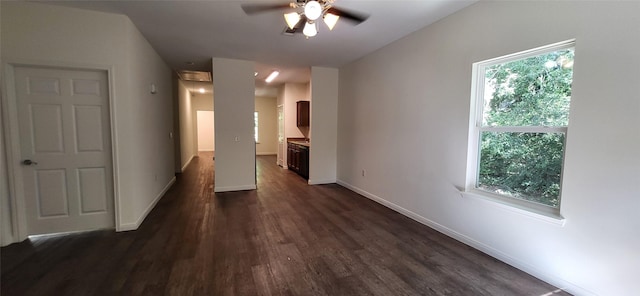 unfurnished room with a healthy amount of sunlight, a ceiling fan, baseboards, and dark wood-style flooring