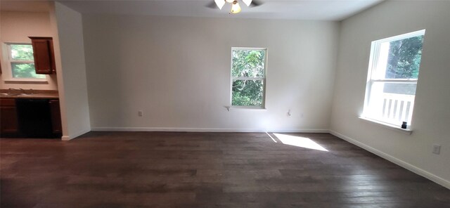 unfurnished room with dark wood finished floors, ceiling fan, baseboards, and a sink