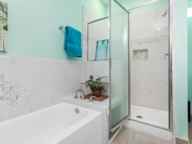 bathroom with tile patterned floors, tile walls, and shower with separate bathtub