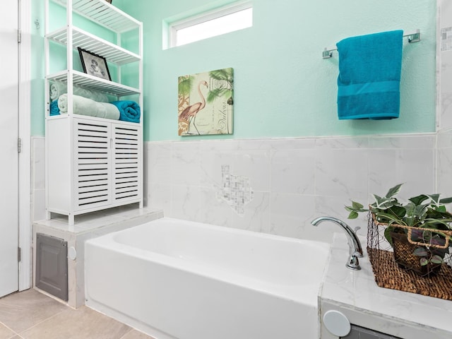 bathroom featuring tile patterned flooring, a tub to relax in, and tile walls