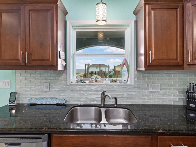 kitchen featuring dark stone counters, sink, stainless steel dishwasher, tasteful backsplash, and decorative light fixtures