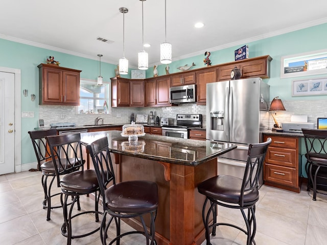 kitchen featuring a kitchen island, ornamental molding, hanging light fixtures, and appliances with stainless steel finishes