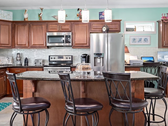 kitchen with a kitchen island, hanging light fixtures, appliances with stainless steel finishes, and dark stone counters