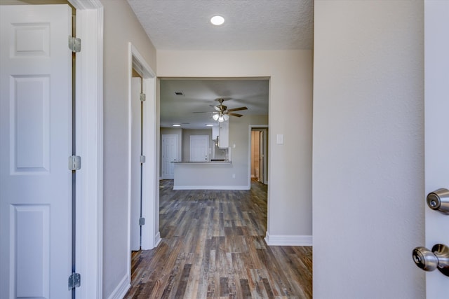 corridor featuring a textured ceiling and dark hardwood / wood-style flooring