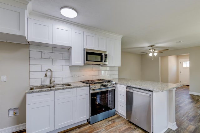 kitchen with white cabinetry, kitchen peninsula, stainless steel appliances, ceiling fan, and sink