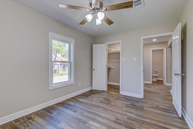 unfurnished bedroom with ceiling fan, light wood-type flooring, a closet, and a walk in closet