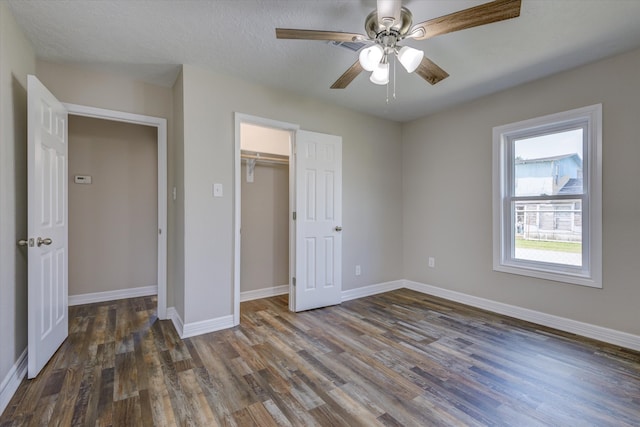 unfurnished bedroom with a closet, ceiling fan, dark hardwood / wood-style floors, and a textured ceiling