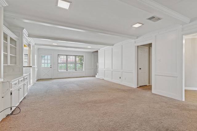 empty room featuring beamed ceiling, light carpet, and ornamental molding