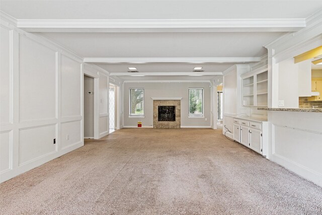 unfurnished living room with crown molding, light colored carpet, and a fireplace