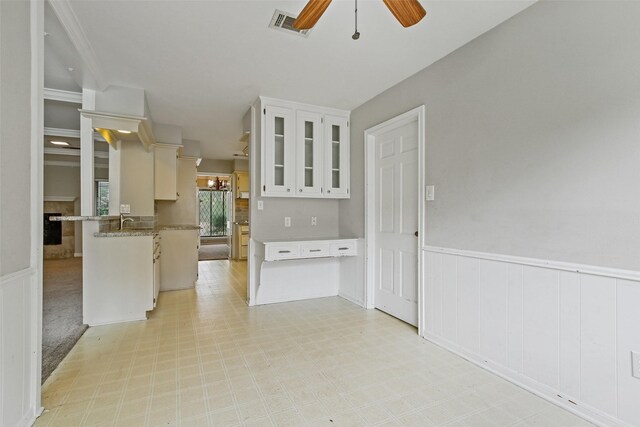 kitchen with kitchen peninsula, sink, ceiling fan, and white cabinets