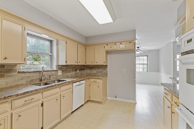 kitchen with light stone countertops, dishwasher, sink, decorative backsplash, and ceiling fan