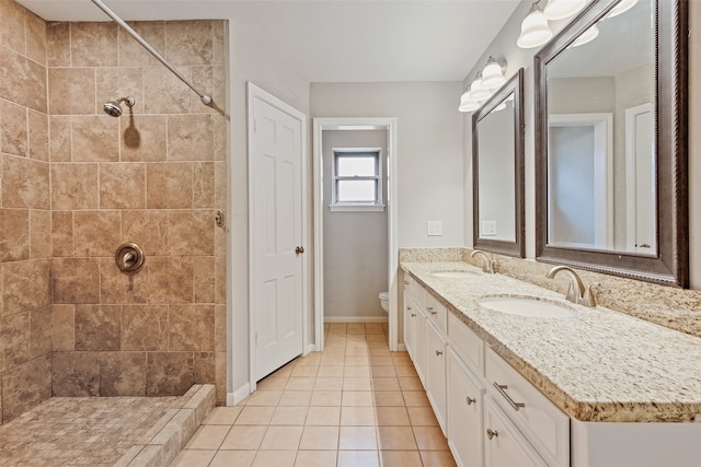 bathroom with tile patterned flooring, vanity, toilet, and a tile shower