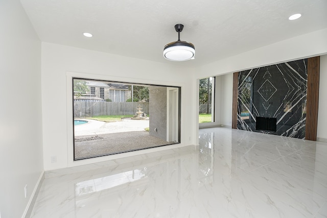 empty room with a wealth of natural light, a textured ceiling, and a fireplace