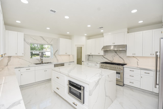 kitchen featuring appliances with stainless steel finishes, white cabinetry, light stone counters, and a center island