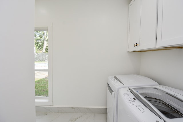 clothes washing area featuring plenty of natural light, cabinets, and separate washer and dryer