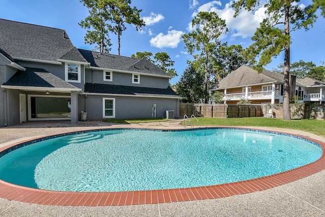 view of swimming pool with central AC unit and a lawn