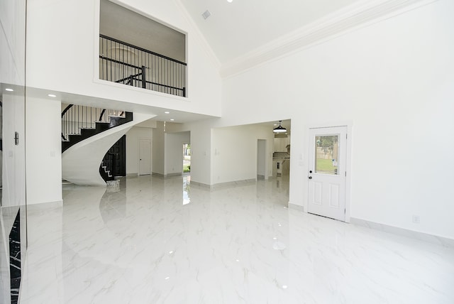 unfurnished living room featuring ornamental molding and a high ceiling