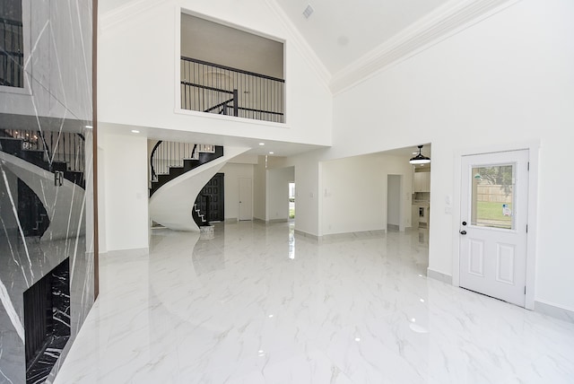 interior space featuring ornamental molding, a high end fireplace, and a towering ceiling