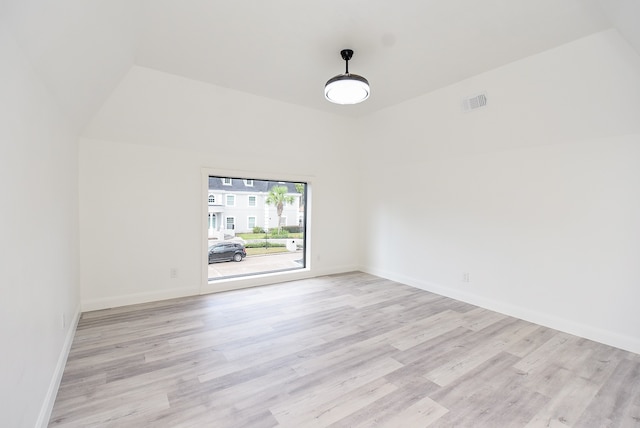 empty room with light wood-type flooring and lofted ceiling