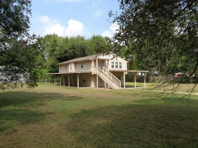 back of property with a carport, stairway, a yard, and a deck