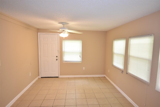 unfurnished room featuring light tile patterned flooring, a ceiling fan, baseboards, and a textured ceiling