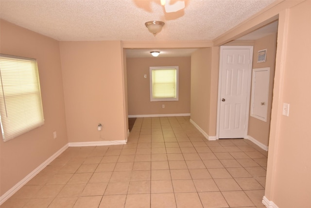 unfurnished room with light tile patterned floors, baseboards, and a textured ceiling