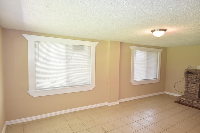 unfurnished room featuring light tile patterned floors, baseboards, and a textured ceiling