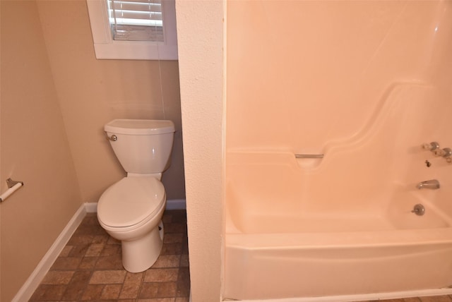 full bathroom featuring stone finish flooring, baseboards, and toilet