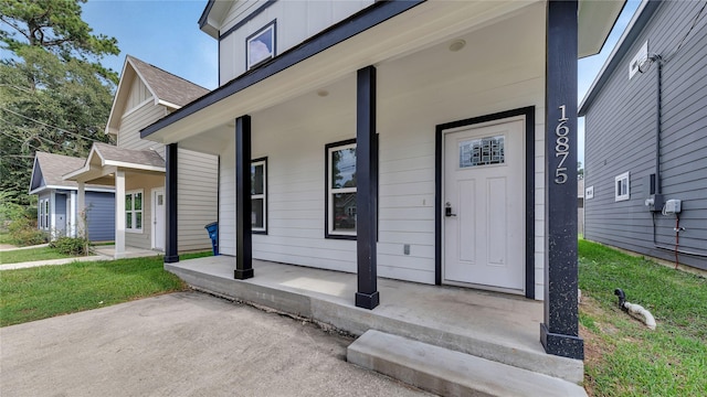 entrance to property featuring roof with shingles and a porch