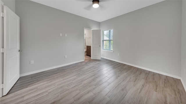 unfurnished bedroom featuring ceiling fan, baseboards, light wood-style floors, and ensuite bathroom