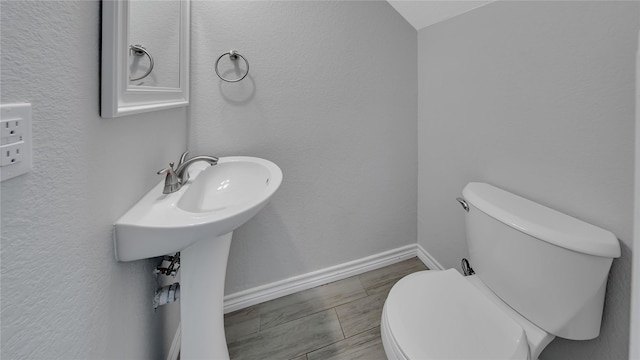 half bath with baseboards and toilet