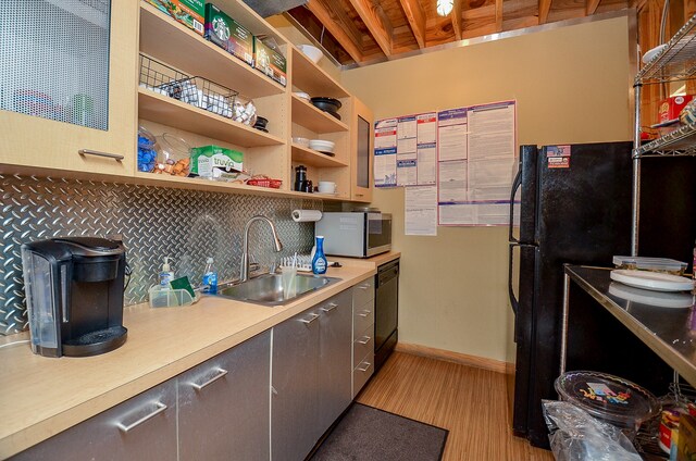 kitchen with light wood-type flooring, black appliances, backsplash, and sink