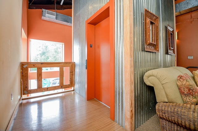 hall with hardwood / wood-style floors, high vaulted ceiling, and elevator