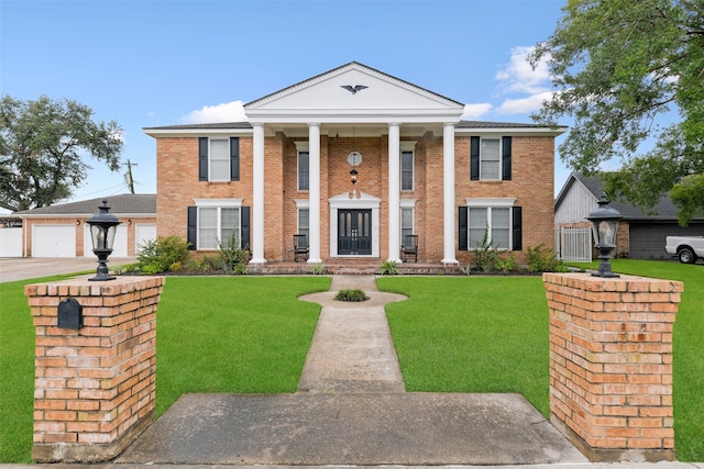 neoclassical / greek revival house featuring concrete driveway, a garage, brick siding, and a front yard