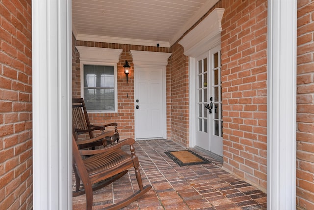 property entrance with covered porch, french doors, and brick siding