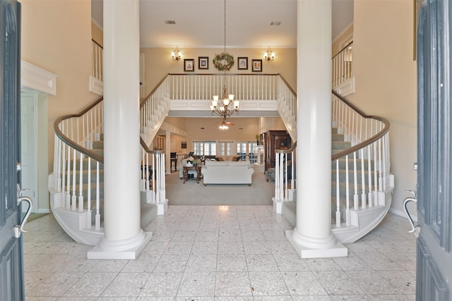 carpeted foyer entrance with decorative columns, an inviting chandelier, and a towering ceiling