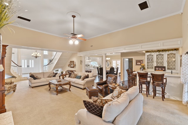 carpeted living room with ceiling fan with notable chandelier and ornamental molding