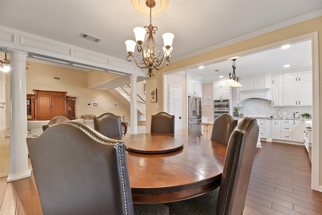 dining area with dark wood-type flooring, decorative columns, an inviting chandelier, and crown molding