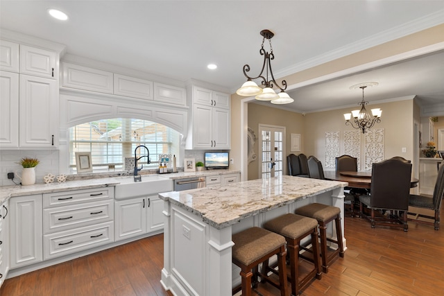 kitchen featuring backsplash, white cabinetry, dark hardwood / wood-style floors, pendant lighting, and a kitchen island