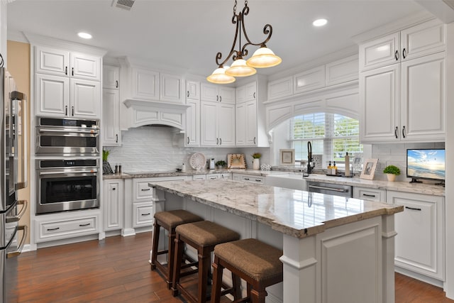 kitchen with pendant lighting, white cabinetry, a kitchen island, dark wood-type flooring, and appliances with stainless steel finishes