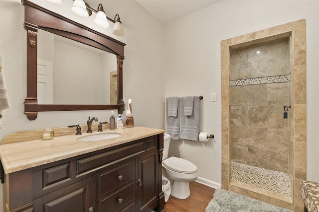 bathroom featuring vanity, toilet, hardwood / wood-style flooring, and a tile shower