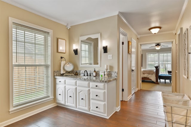 bathroom featuring wood-type flooring, ceiling fan, ornamental molding, and vanity