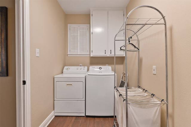 laundry area featuring separate washer and dryer, wood-type flooring, and cabinets