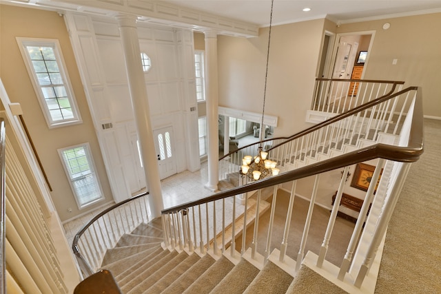 interior space with decorative columns, ornamental molding, an inviting chandelier, and a towering ceiling