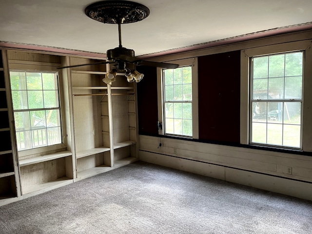 unfurnished bedroom featuring carpet flooring, multiple windows, and wooden walls