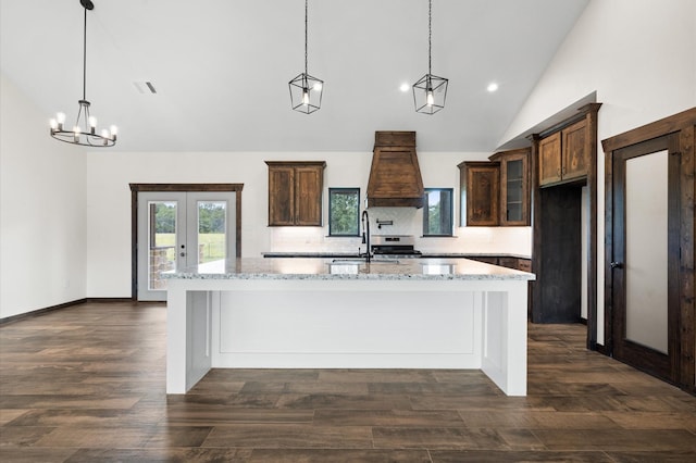 kitchen with a large island with sink, light stone countertops, hanging light fixtures, and dark hardwood / wood-style floors